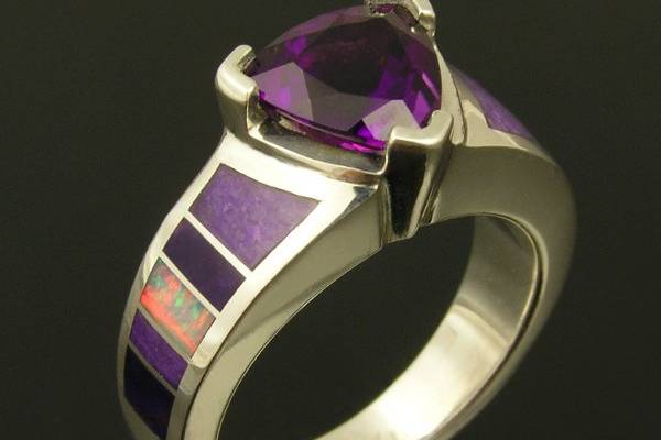 Sterling silver ring featuring a 1.6 carat Amethyst accented by Australian opal and sugilite inlay. Inlaid lavender and purple sugilite combine with red Australian opal for a striking accent to the 8mm trillion cut purple amethyst. The ring is a size 6 ¼ and is available in other sizes and color combinations by special order.