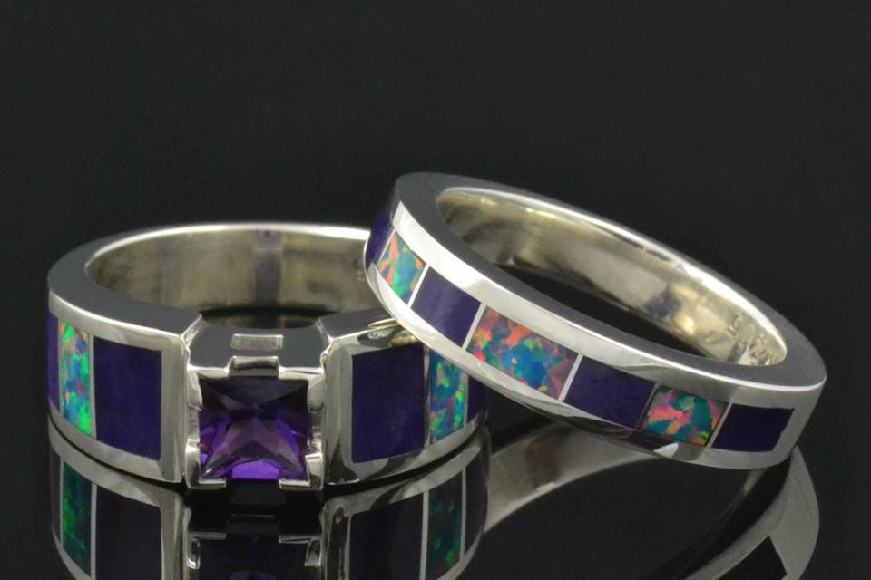 Amethyst engagement ring inlaid with purple sugilite and lab created opal in sterling silver.  The center stone is a .65 carat princess cut amethyst.  The wedding band is inlaid with lab opal and sugililte to match. This set is available in other inlay materials and with other center stone choices.  This wedding set will be made to order in your ring size in 3 to 6 weeks.