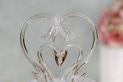 This beautiful wedding cake topper features a pair of artisan made blown glass swan accented with 24K gold, and a heart. The front of the cake topper also features a flower ornament accented with white enamel. Skirt is made of organza. Perfect for a beach or ocean themed wedding!
SKU: 100260
$52.95
http://www.weddingcollectibles.com/Glass-Swan-Cake-Topper-with-Heart-p-283.html