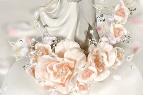 This stunning recreation vintage cake topper features a sprig of velvet roses accented with faux pearls and crystals. This elegant fine porcelain couple is hand painted and features a glazed finish. Base is wrapped in moire and accented with silk cording.
Roses available in Peach and Mauve
$89.95
http://www.weddingcollectibles.com/Vintage-First-Kiss-Wedding-Cake-Topper-Peach-and-Mauve-Availab-p-1761.html