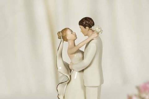 This stunning recreation vintage cake topper features a sprig of rhinestone studded roses in a sea of faux pearls accented with fine gold wiring. The elegant off-white fine porcelain wedding couple features the bride carrying a delicate handmade bouquet, and 24K gold trim on her veil and bouquet.. Base is wrapped in moire and accented with silk cording.
$89.95
http://www.weddingcollectibles.com/Vintage-Rose-Pearl-Wedding-Cake-Topper-p-1757.html