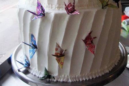 Three tiered cake with buttercream frosting and paper cranes.