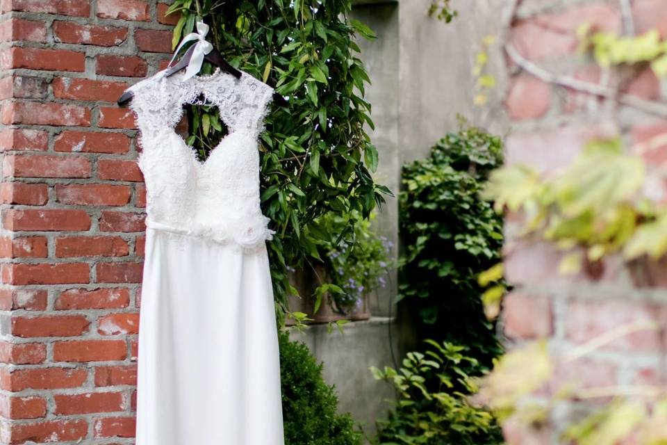 Wedding dress hanging by brick wall