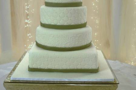 Five tiers of ivory colored cakes topped with sugar paste jewel toned roses.  Green fondant bands encircle each cake.