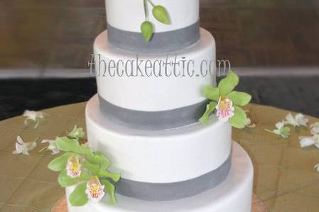 Four tier fondant cake with silver sugar ribbons and green orchids.