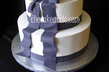 Simple buttercream cake with sugar ribbon and bow in the deep navy used in wedding decorations.