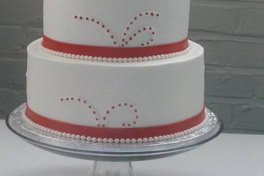 Three tier wedding cake with buttercream icing.  Handmade gumpaste roses with fondant ribbon for border on each tier.