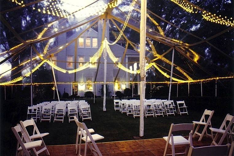 A night wedding we did a very long time ago, with jewel net lighting, white wood chairs, a dance floor and a clear tent top so you can see the night sky through it.