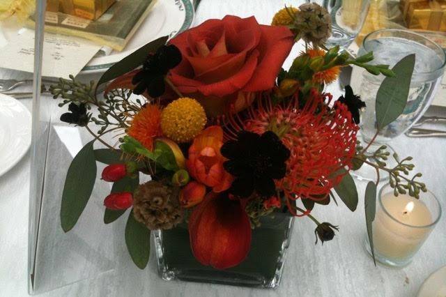Assorted formal blooms in warm Autumn hues and texture and interest to this table top decor