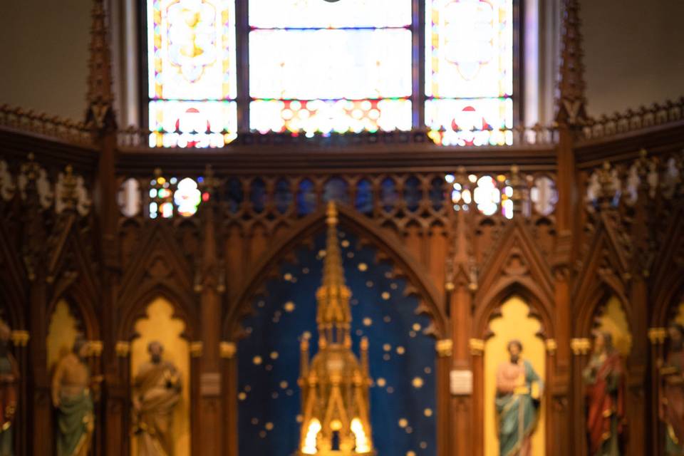 Church ceremony at 620 Loft & Garden, NYC – the bride and groom are seated before the breathtaking golden altar in an intimate religious ceremony.