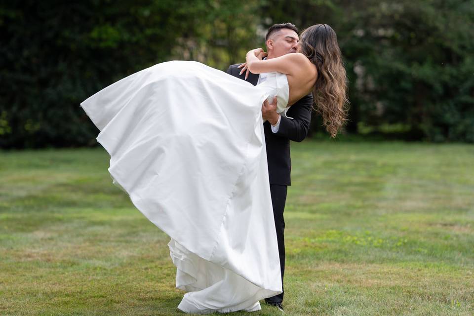 Romantic lift at CV Rich Mansion, NYC – the groom sweeps his bride off her feet in a joyful outdoor portrait on the mansion grounds.