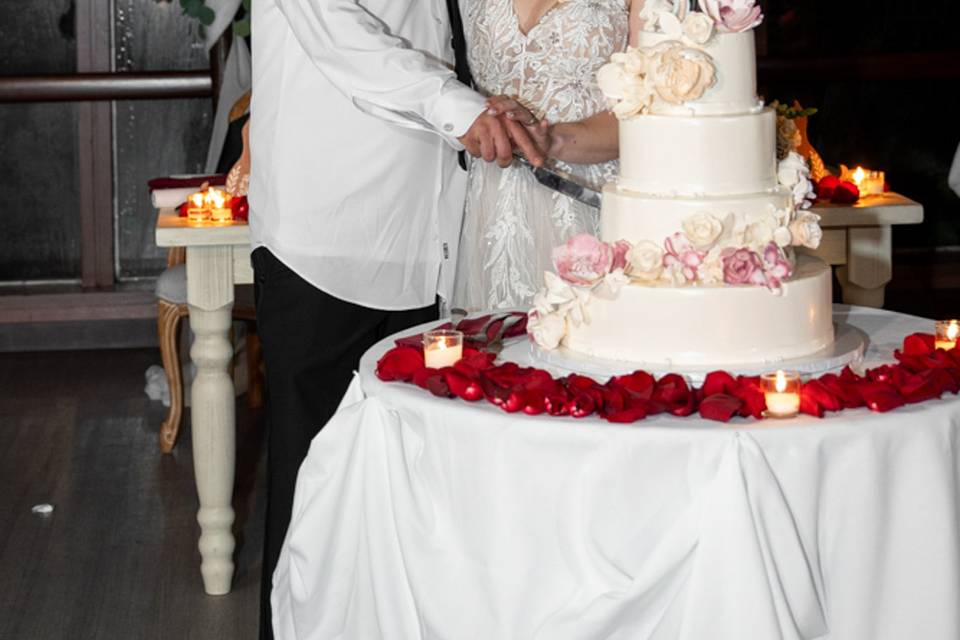 Cake cutting kiss at Pavilion at Sunken Meadow, NY – the couple shares a sweet kiss surrounded by florals during their reception.