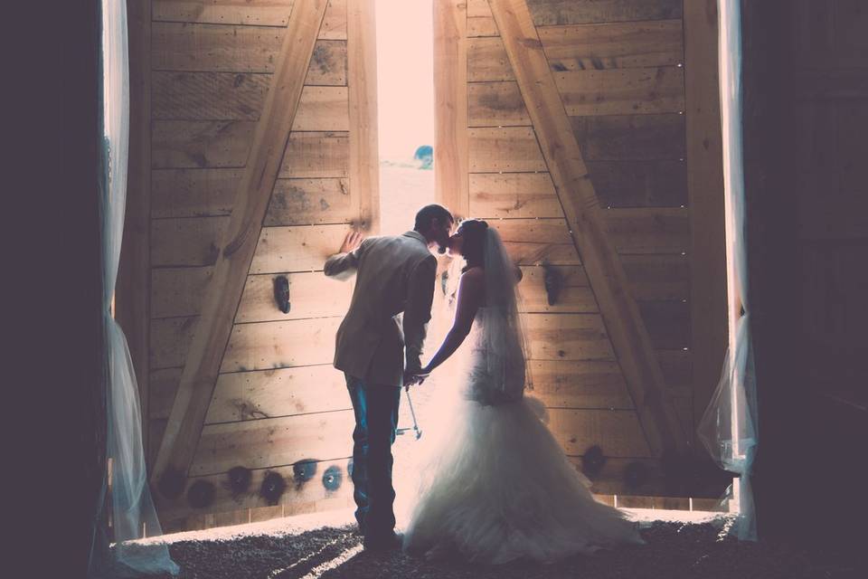 Newlyweds kiss as they exit the barn