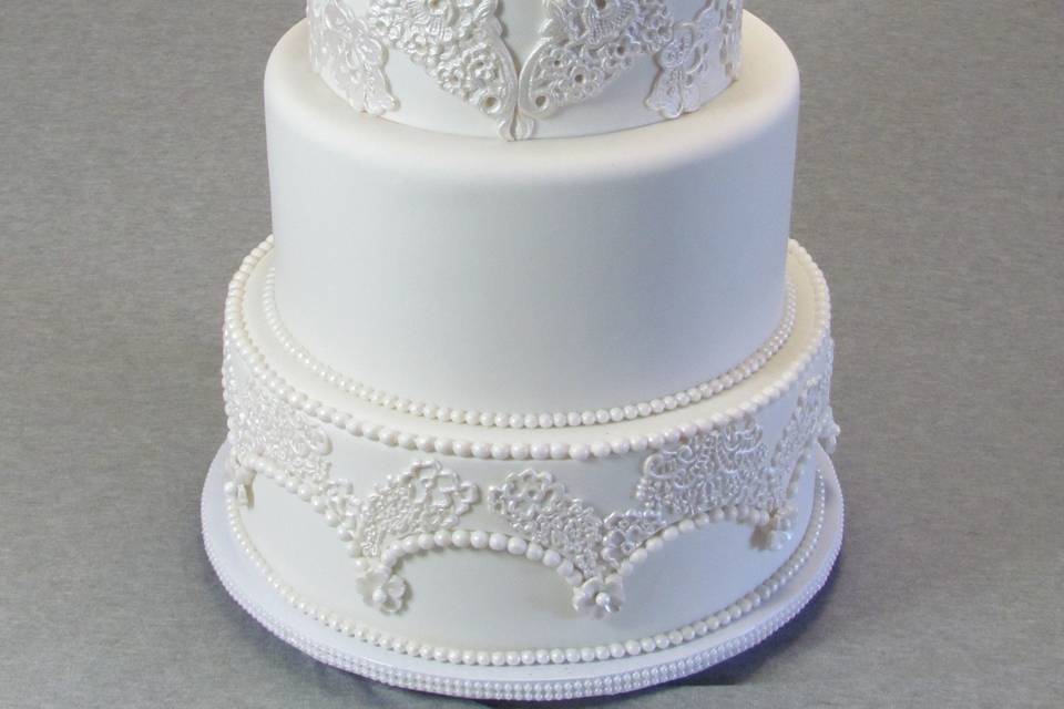Elegant life like sugar roses on top of white classic wedding cake with laces