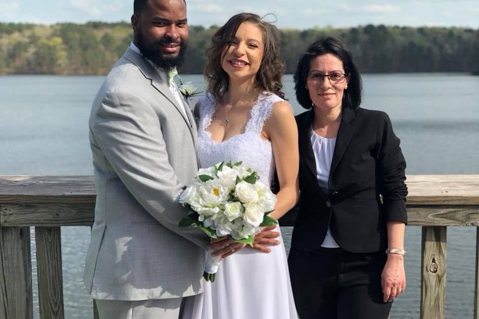 Couple and officiant by the lake