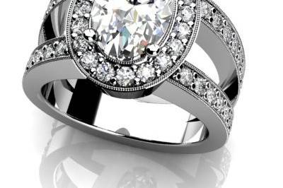 Custom white gold or platinum diamond engagement ring.  Oval center diamond with diamond halo, split shank, and mill grain.