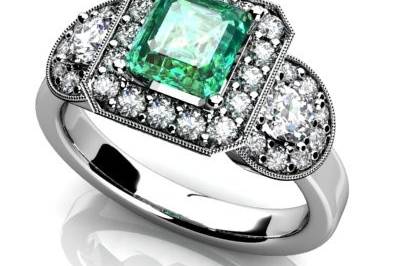 Custom three stone emerald engagement ring. Diamond halos and half moon cut diamonds on each side. Vintage look with mill grain.