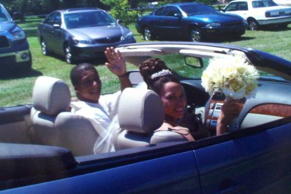 The couple riding their bridal car