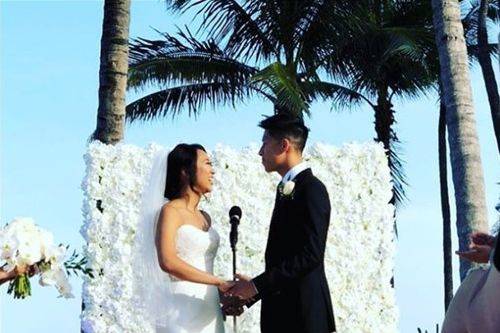 Newlyweds with flower wall backdrop