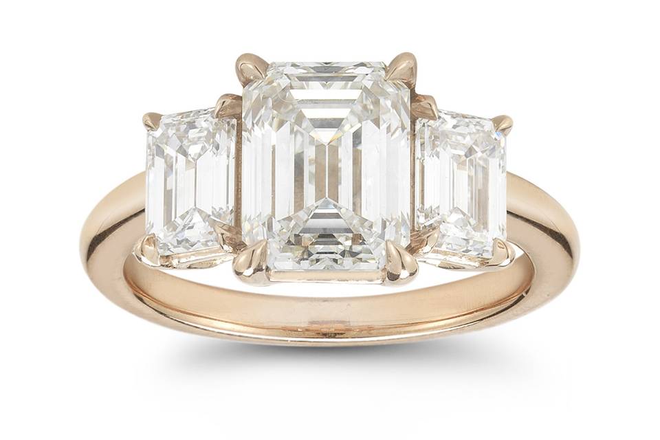 This three stone emerald cut diamond engagement ring features a 2.20 carat center diamond flanked by 1.05 total carat weight emerald cut diamonds. Shown in 18k rose gold, this ring can be created in platinum and 18k yellow gold.