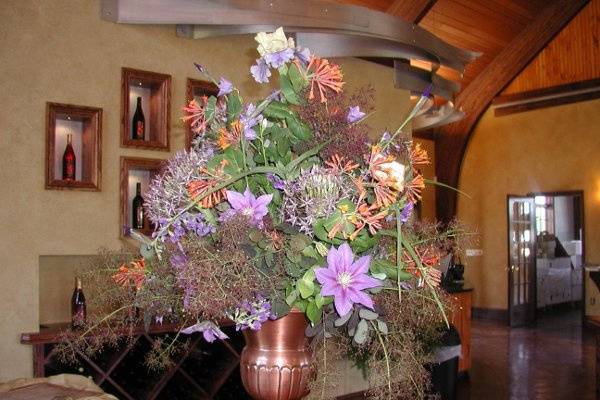 Bright copper urn at a local winery event features clematis, honeysuckle, smoke tree, iris, allium and campanula.
