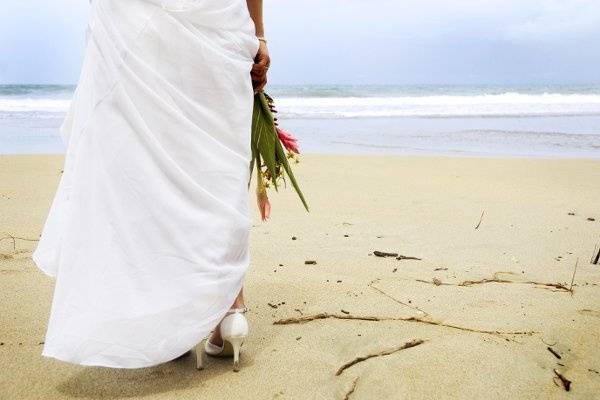 A bride holds her tropical bouquet on the white beaches of Costa Rica just before walking down her sandy aisle to her groom.