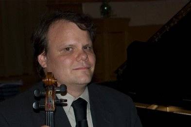 Eric Ortner, Violin Virtuoso sits in front of a piano