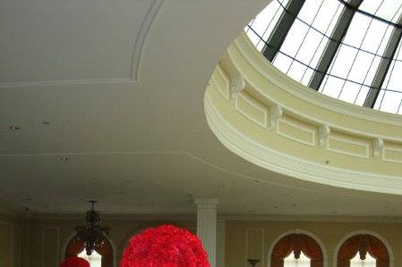 High centerpieces designed with a ball of red carnations atop a clear glass cylinder filled with a spiral of red roses by Stein Your Florist Co.