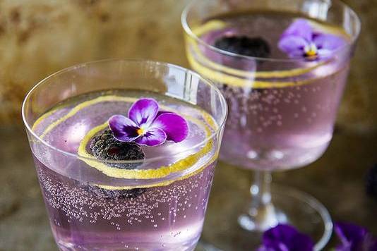 Lavender Gin fizz with fresh flowers and blackberries floated with a lemon twist