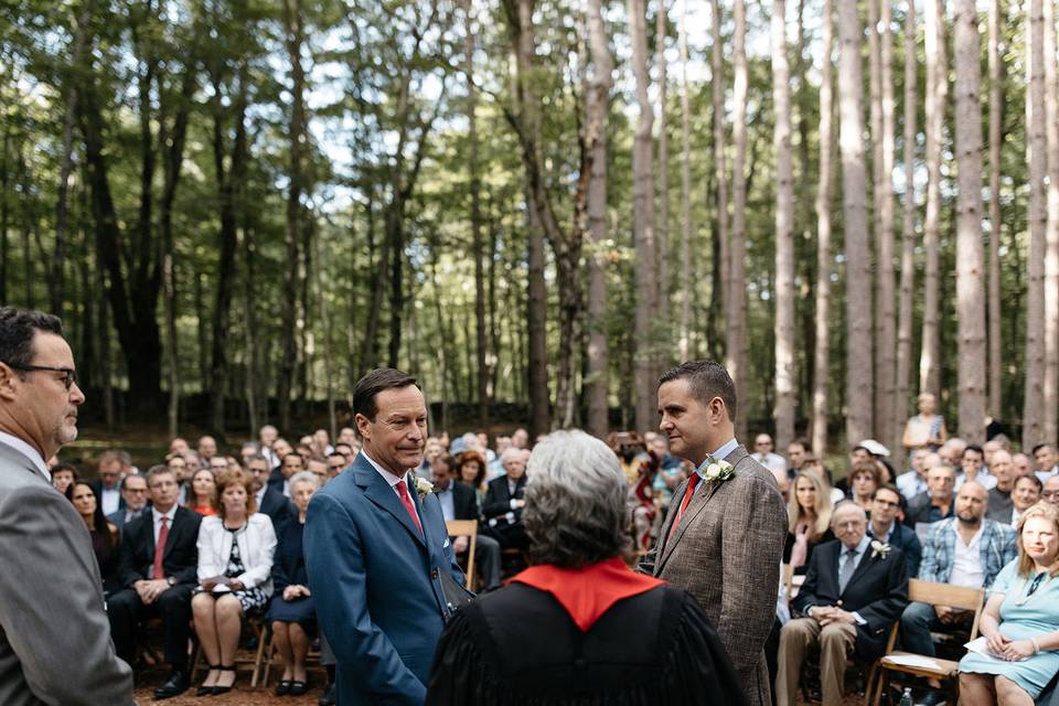 Two grooms getting married in the pine grove at The Roxbury Barn & Estate. Photo by Jean-Laurent Gaudy.