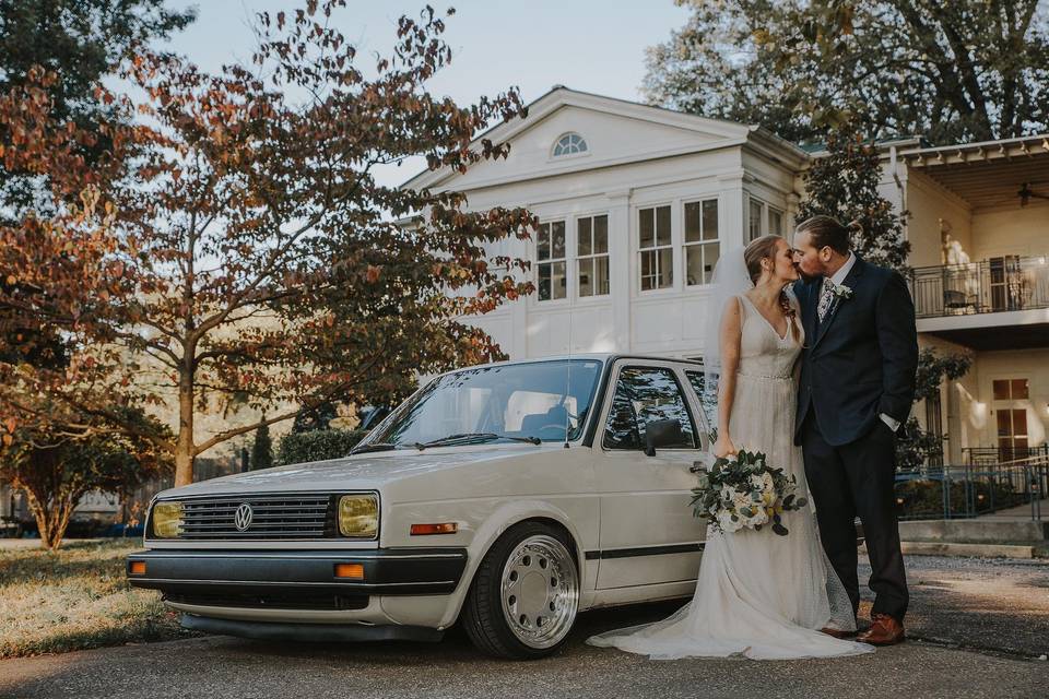 Newlyweds kissing by the car