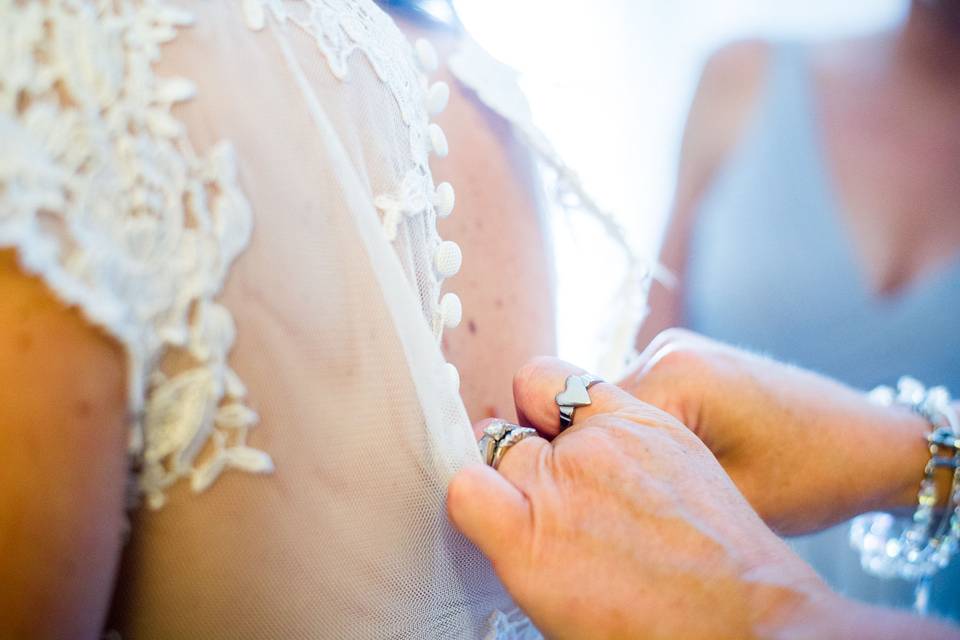 Kelsey's mom helps with the buttons on her beautiful wedding dress.
