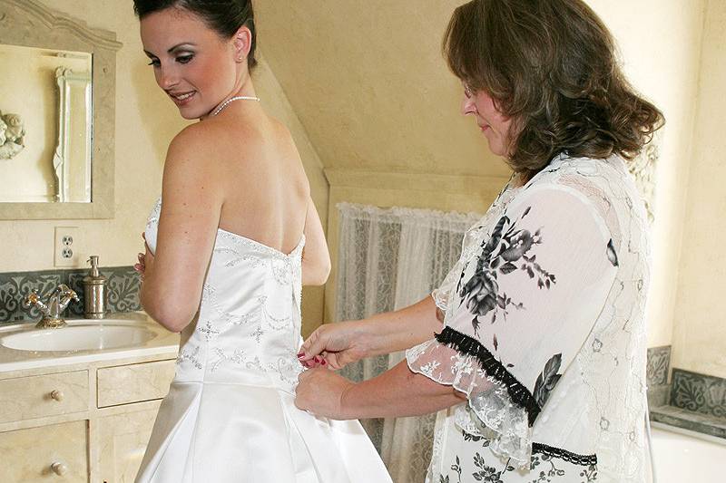 Mother of bride helping with wedding dress zip up.