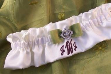 Satin bridal garter accented with a filigree rhinestone button and personalized with an embroidered monogram