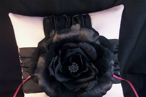 Black silk rose with center rhinestone button on a light pink satin ring bearer pillow.