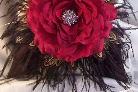 Gorgeous ring bearer pillow in chocolate satin with black ostrich feathers and pheasant feathers with a ruby red rose embellished with a sparkling rhinestone button.