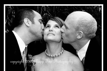 Black and white photo of bride getting kissed by the groomsmen.