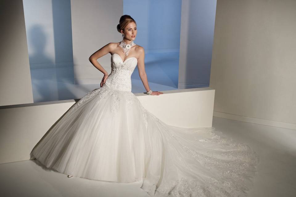 Y21142 - Carlotta <br>
A celebration of romance is captured in this lovely A-line misty tulle and lace gown. Carlotta showcases a deep sweetheart neckline with tulle draping and elegant hand-beaded lace appliqués under the bust. Lace appliqués continue through the bodice and flow into the dramatic tulle skirt. A sweep train and functional corset back complete this remarkable gown.