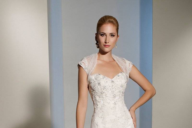 Y11214 - Felicita
Intricate lace detailing on point d’esprit denotes this stunning two-piece dress set. Felicita offers a superbly hand-beaded bodice and sweetheart neckline with a richly embellished point d’esprit cap sleeve bolero jacket to match. Romance resonates from this slim A-line gown and will wow your Prince Charming with a semi-illusion chapel length train. Felicita also boasts a functional corset back and removable straps.
