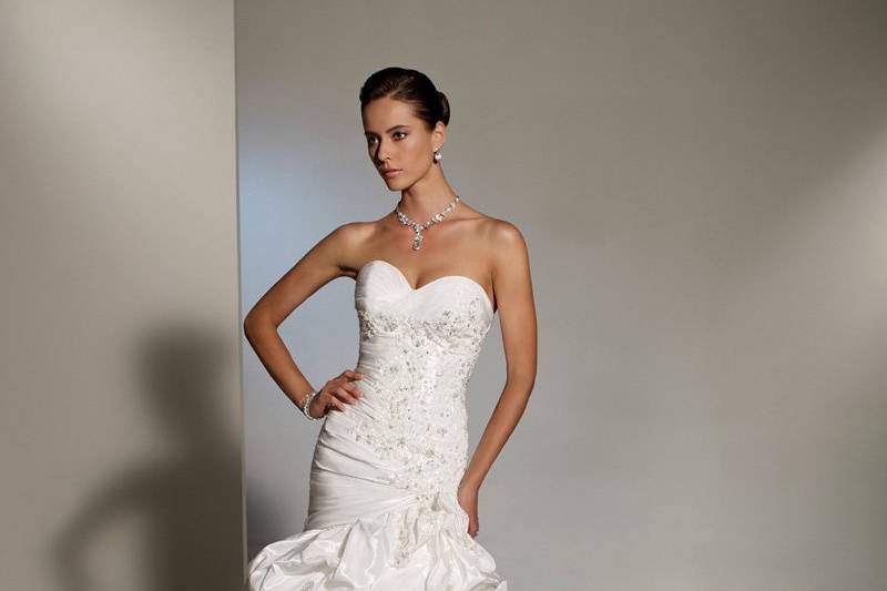 Y11206 - Odelita <br>
Make an unforgettable entrance in chic Monet taffeta, lace and misty tulle. Odelita offers a flattering sweetheart neckline and couture-inspired ruched bodice combined with Swarovski crystal hand-beaded lace that showcases an asymmetrically dropped waistline. Odelita also features a tulle and lace underskirt framed by rich bustled taffeta that flows softly into a pick-up chapel train. A functional corset back and removable straps finish off this modern style.