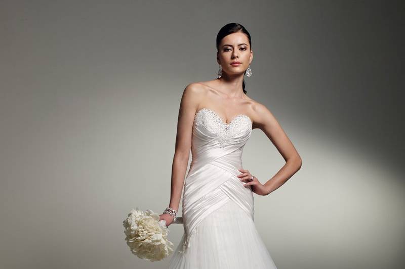 Y21254 - Babette <br>
Featuring classic styling and time-honored design, Babette offers a strapless sweetheart neckline encrusted with crystal hand-beading and delicate lace appliqués. Paris satin draping creates a figure-flattering line throughout the bodice and asymmetrically falls onto the misty and diamond tulle skirt, also accentuated with lace appliqués. A functional corset back and chapel length train finish the gown. Removable straps included.