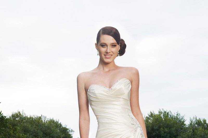 Y11320-Maysilee <br>
Dream taffeta culminates into a gown worthy of the most glamorous bride. Sparkling crystal beading peeks out from the strapless sweetheart neckline and cascades down the bodice and skirt. Maysilee features a flourish of folds and pleats, highlighting the exceptional design of the skirt and chapel length train. A corset back closure and removable straps are included.