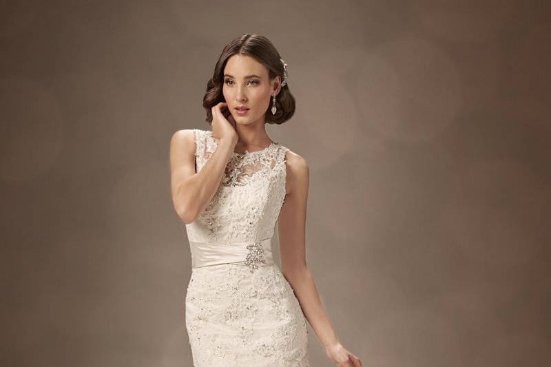 Y11321-District <br>
For the chic, sophisticated bride, this A-line gown makes a bold statement with sleek dream taffeta draped through the bodice, hugging the hips, and gently falling into soft pickups throughout the skirt and chapel length train. District also offers a crystal hand-beaded lace Empire bodice with a Queen Anne neckline, cap sleeves and open keyhole back. A corset back closure is also included.