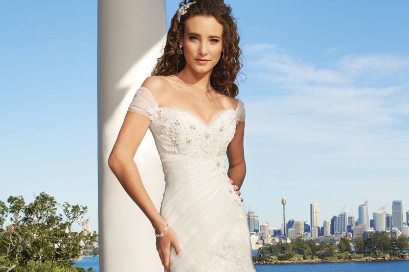 Y11326-Cornucopia <br>
Traditional with an exclusively modern twist, Cornucopia features glorious Guipure lace on a draped fantasy organza bodice. The fit and flare silhouette is cut to enhance the figure and boasts a sweetheart neckline with ruched organza off-the-shoulder sleeves. Lace appliqués follow the line of the bodice and cascade into the rich skirt with chapel length train. Scattered hand-beading adds a touch of sparkle to this delightful gown. A corset back closure is also included.