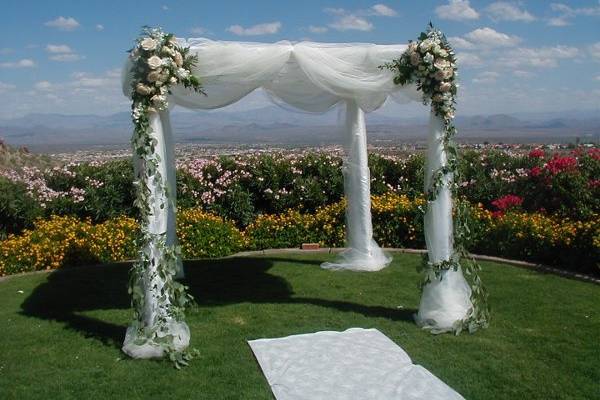 Chuppah with satin draping and tulle overlay has fresh floral accents to create color and dramea