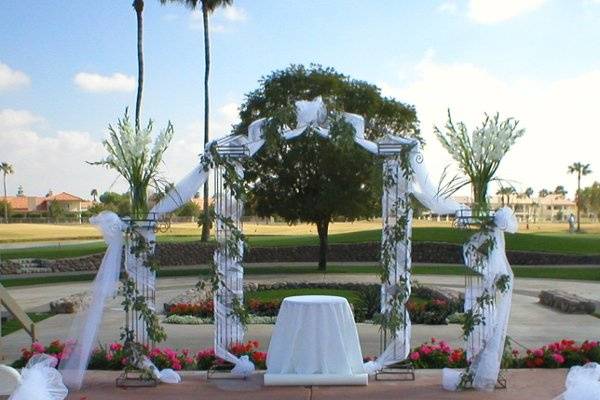 Iron column arch with side columns has added tulle wrap and fresh eucalyptus garland