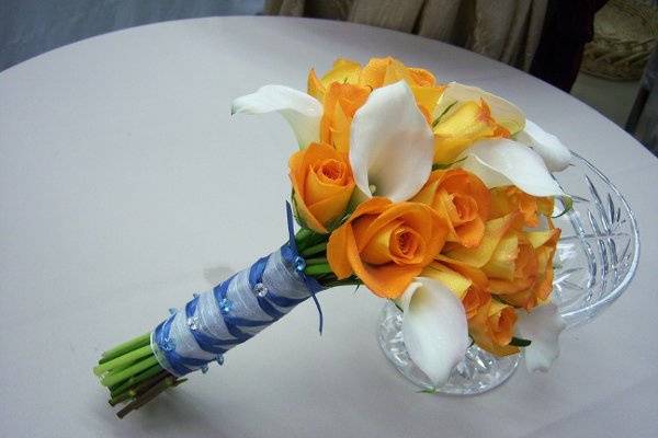 Ivory calla lilies and bright orange roses are the perfect foil for the periwinkle french handle wrap and crystals