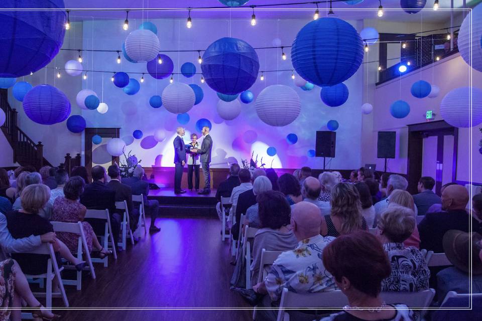 The Main Ballroom is a wonderful, large gathering space. Perfect for wedding Ceremonies, Receptions, Galas, lectures, presentations, play readings, workshops, and celebrations, this room can fit 125 for a cocktail reception or 100 seated guests (chairs and tables in picture shown). The room measures 39' X 39' and has 6 different entrances and exits. This marvelous hall features a wrap around balcony along three sides, a stage, a baby grand piano, and a projection wall (high-quality Epson projector available to rent for an additional fee).Located on our main floor, this room is completely ADA-accessible and ready for your event.