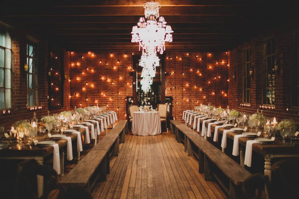 Beautiful and romantic reception space at Carondelet House with farmhouse table settings spaced with silver mercury glass vases filled with white hydrangea and babys breath.