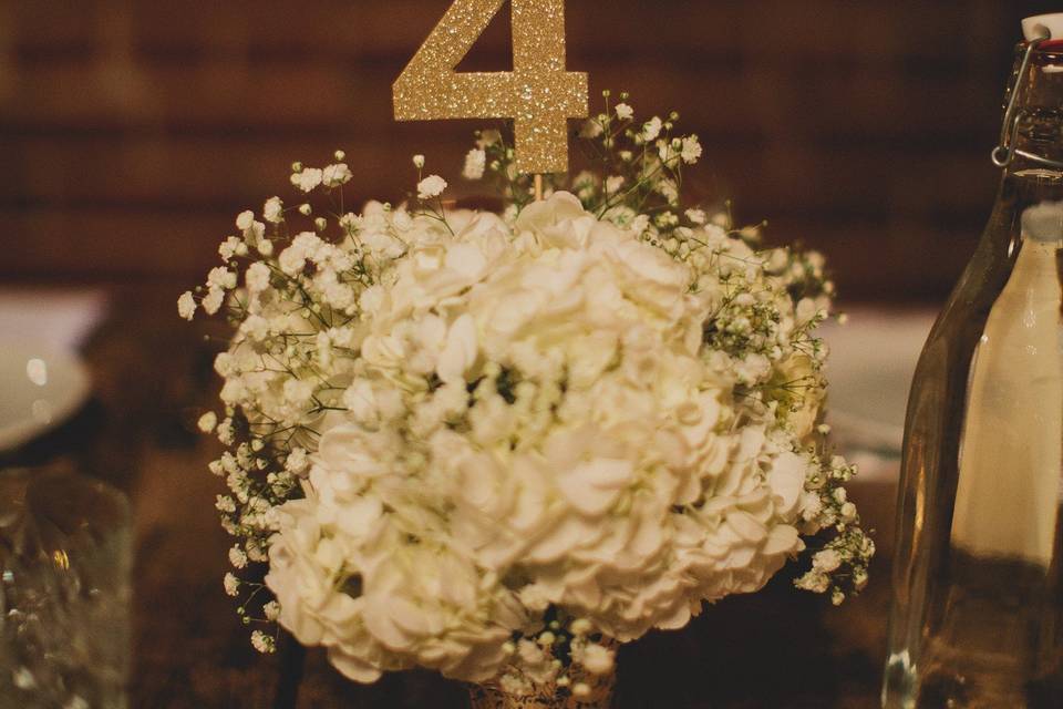 Beautiful and romantic reception space at Carondelet House with farmhouse table settings spaced with silver mercury glass vases filled with white hydrangea and babys breath.